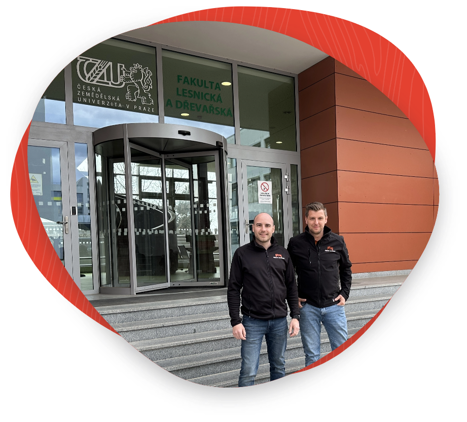 Tomáš Lesina a František Vostál stojí před vchodem Fakulty lesnické a dřevařské České zemědělské univerzity v Praze, s logem firmy specializující se na sanaci krovů na jejich oblečení.